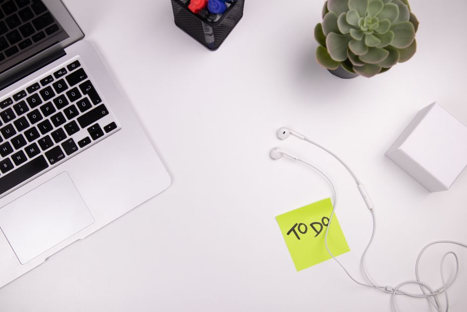 Espace de travail organisé avec un ordinateur portable, des écouteurs, une plante et une note autocollante "TO DO".
